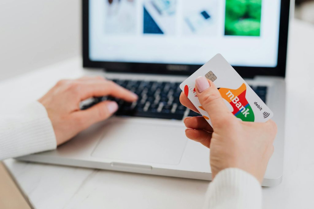 Close-Up Shot of a Person Using a Laptop while Holding a Credit Card