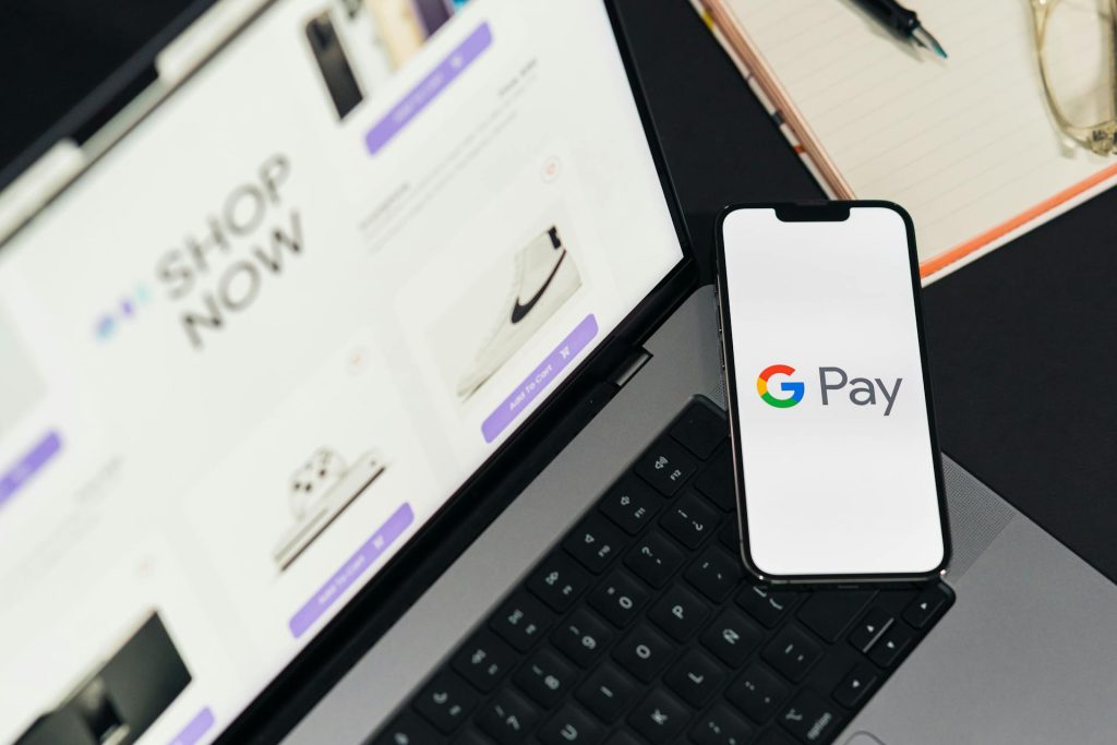 Smartphone displaying Google Pay placed on a laptop with an online shop open on the screen