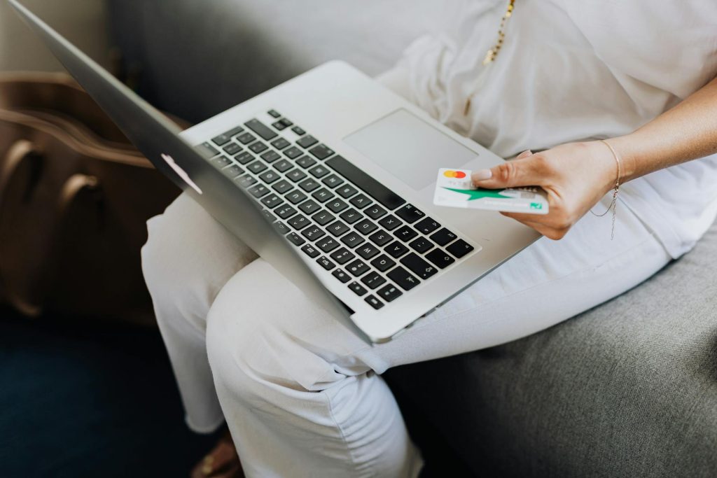 Person holding a credit card while using a laptop for online shopping