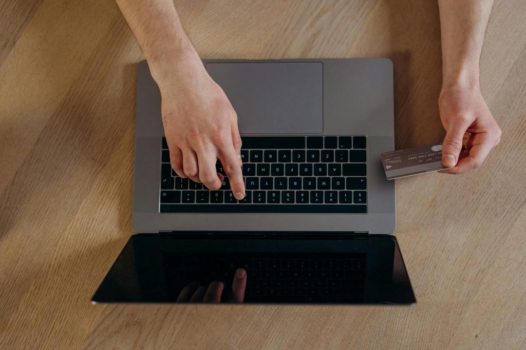 Person entering payment details on a laptop while holding a credit card