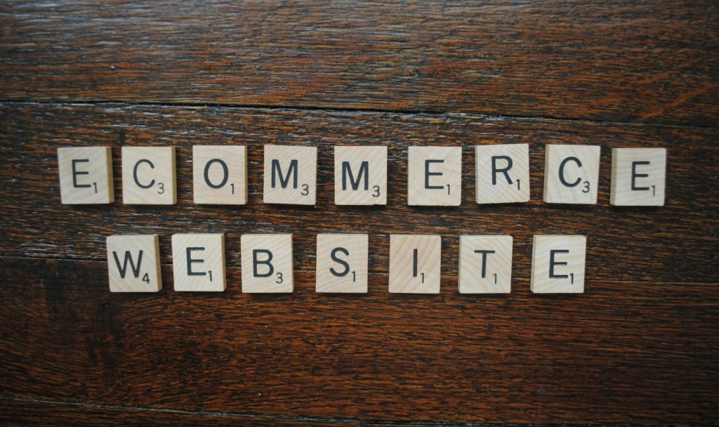 Scrabble tiles arranged on a wooden surface spelling “ECOMMERCE WEBSITE”